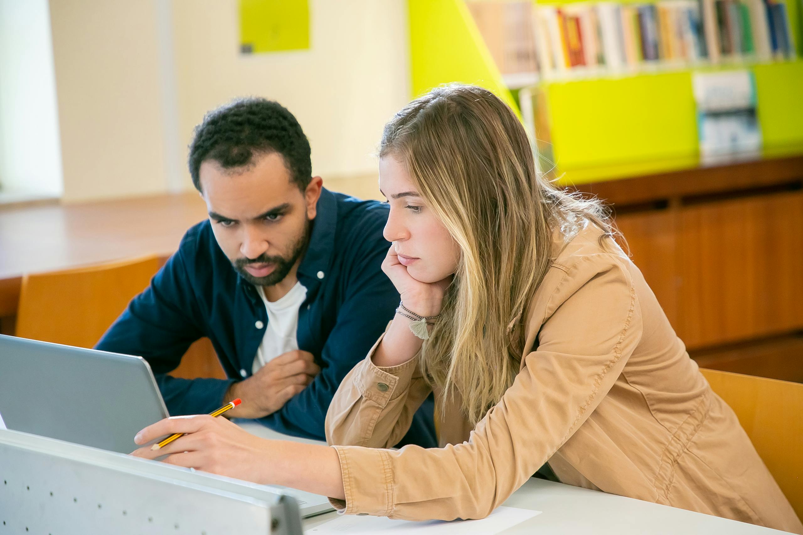 Concentrated multiracial classmates using laptop for studies while doing homework assignment together in university